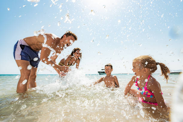 Playful family having fun while splashing in the sea. stock photo