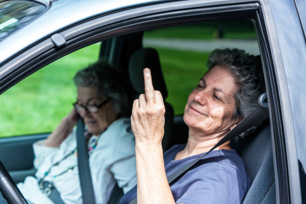 Playful Senior Adult Daughter and Elderly Mother Sitting in Car stock photo