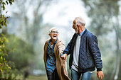 Cheerful senior couple having fun in the park. Focus is on woman. Copy space.