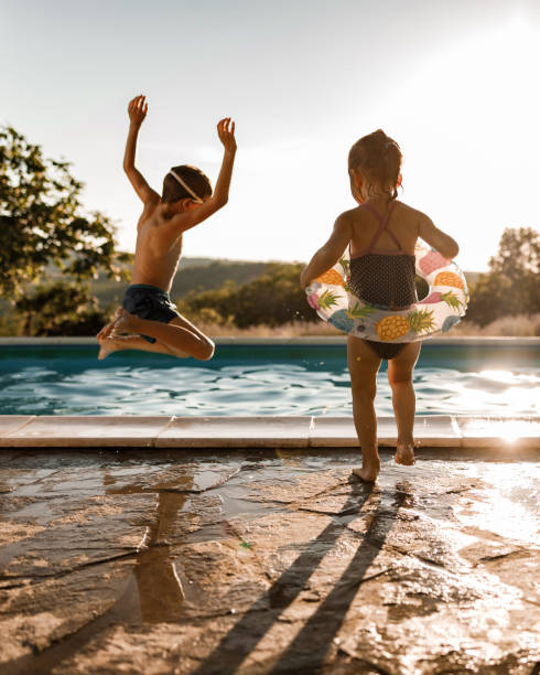 Playful siblings having fun during summer day at the pool. stock photo