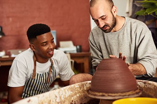 Shot of two young men working with clay in a pottery studio