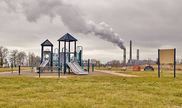 Playground With Factory Smokestack Billowing Pollution In The Background stock photo