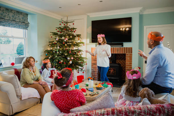Playing Charades At Christmas Family are playing charades at christmas time in the living room of their home. It's the mother's turn and everyone is trying to guess. charades stock pictures, royalty-free photos & images