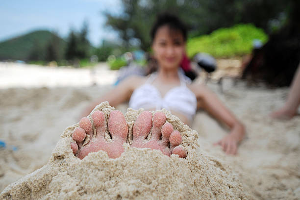 Playing Sand On Beach - XLarge A happy girl playing sand on beach human feet buried in sand. summer beach stock pictures, royalty-free photos & images