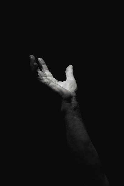Pleading for help Hand emerging from the dark. Help wanted. Black and white human arm stock pictures, royalty-free photos & images