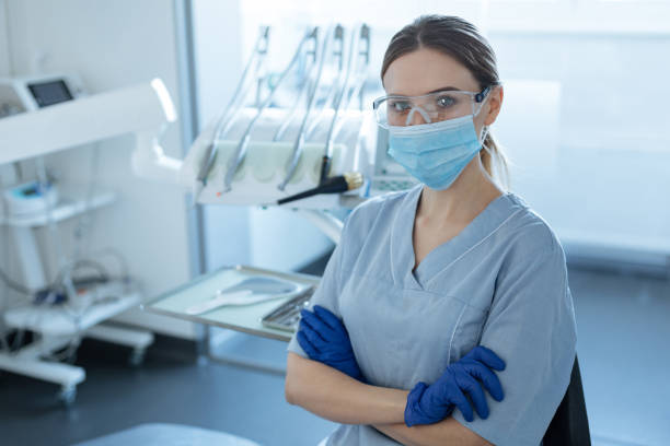 pleasant female dentist posing in safety goggles and face mask - aluno dentista imagens e fotografias de stock