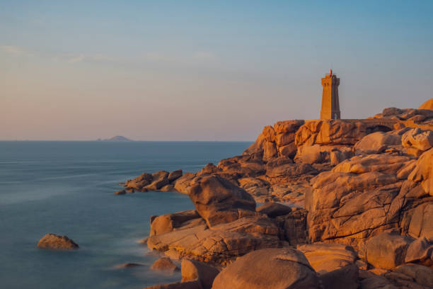 Ploumanach lighthouse at the pink granite coast in Brittany, France during sunset stock photo