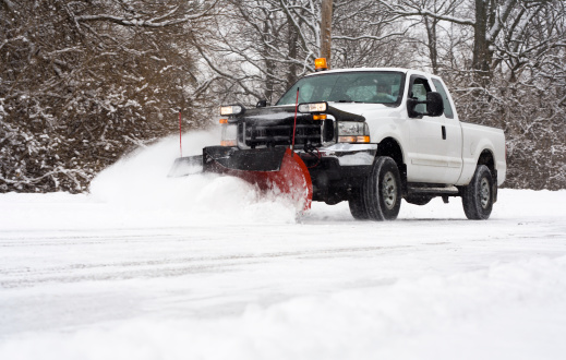 Man in pickup truck plowing road during snow storm