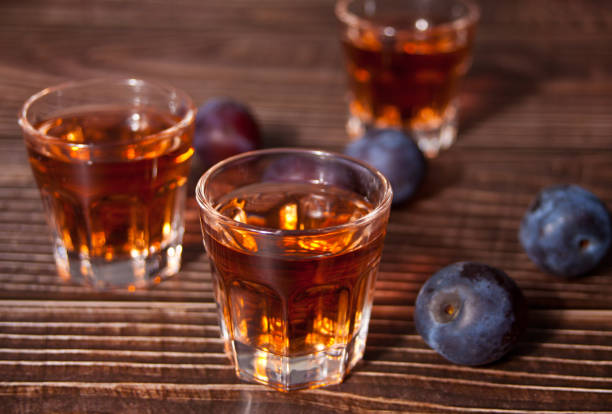 Plum vodka or brandy with fresh plums on the wooden table. stock photo