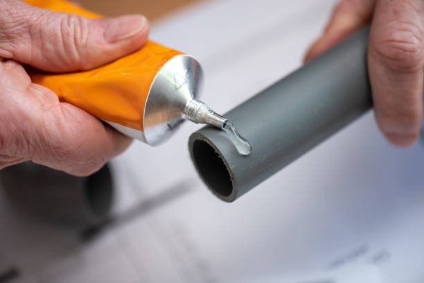 Plumber applying glue on pvc pipe stock photo