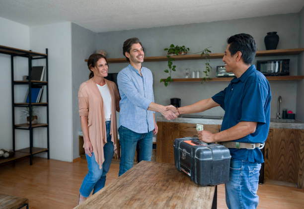 Plumber greeting happy clients at home with a handshake stock photo