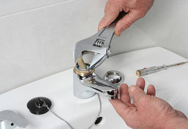 Plumber repairing the faucet of a sink. stock photo