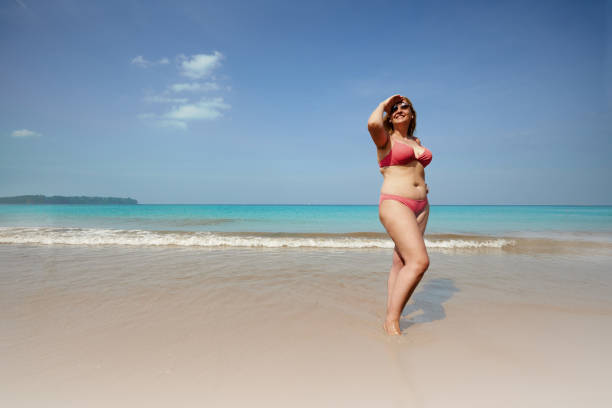 Plus size female tourist enjoying vacation on sandy seacoast stock photo