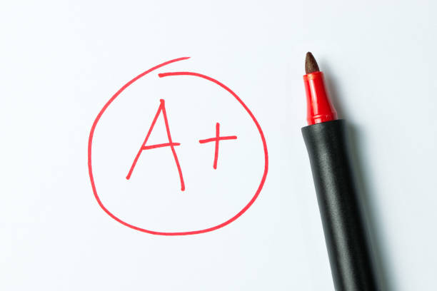 A plus written with red pen A plus grade written in red, on notebook paper with the pen sitting there. test results stock pictures, royalty-free photos & images