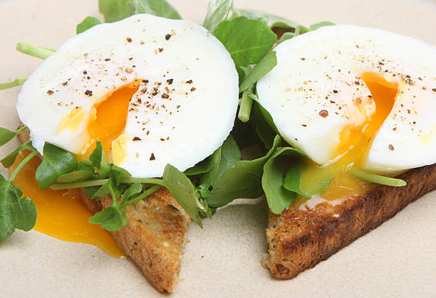 Poached Eggs on Toast Poached eggs with watercress on toasted wholemeal bread. poached food stock pictures, royalty-free photos & images