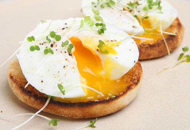 Poached Eggs on Toasted English Muffin Two poached eggs on a toasted English muffin. poached food stock pictures, royalty-free photos & images