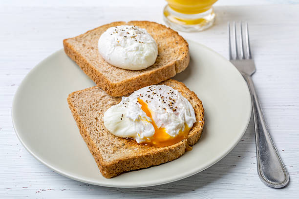 Poached Eggs on Whole Grain Bread Toasts Poached Eggs on Whole Grain Bread Toasts poached food stock pictures, royalty-free photos & images