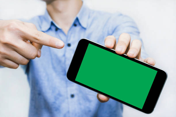 Pointing finger to Green screen smart phone is a template to use for your best content. Pointing finger to Green screen smart phone is a template to use for your best content. Blue business shirt smart phone green background stock pictures, royalty-free photos & images