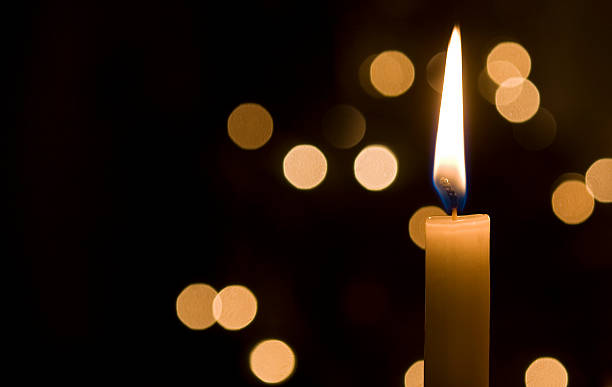 Points of light in the darkness a single candle lit at night and in the background are light reflections memorial event stock pictures, royalty-free photos & images