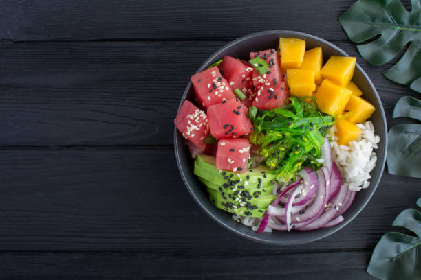Poke bowl with tuna in the black bowl on the tropical background stock photo