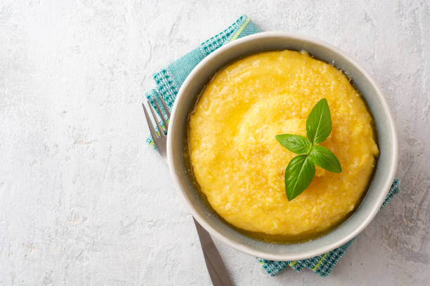 Polenta with butter and parmesan cheese in bowl on concrete background stock photo