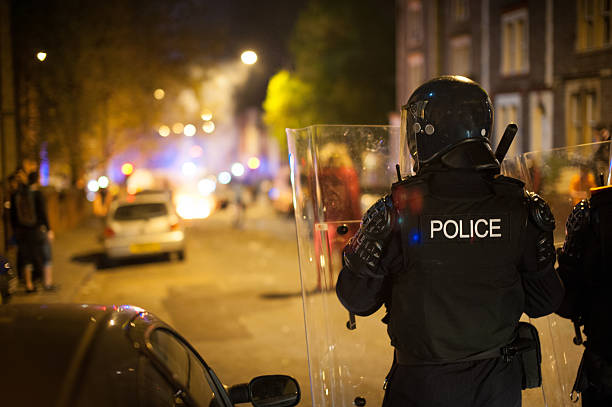 Police defending riot Riot police move forwards towards burning waste bins and rioting. riot stock pictures, royalty-free photos & images