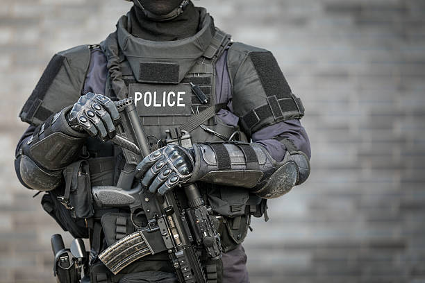 swat police officer against brick wall - wapen apparatuur stockfoto's en -beelden