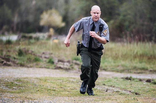 An on duty law enforcement officer, working hard at providing justice, keeping the peace, and making the country a safer place.  Here, the policeman runs to the scene of an emergency.