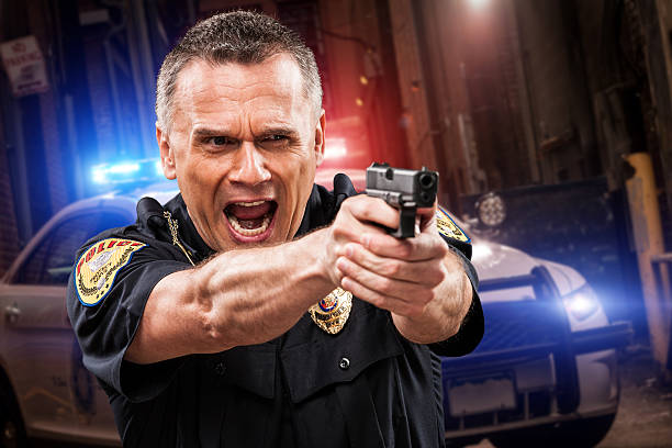 Police Officer in Alley with Gun Drawn Yelling Orders stock photo