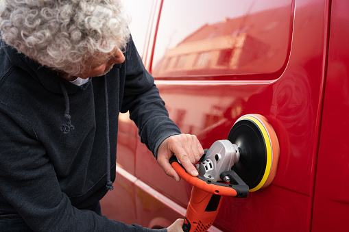 Photography of a mature man polishing a car with an electric orbital polisher.
Photography was taken in 47 megapixels with 50 mm f/1.4 outdoors in Germany.