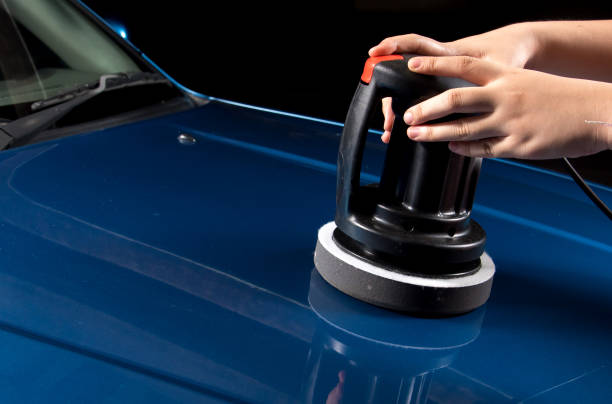 Polishing the blue car with polish machine in the garage