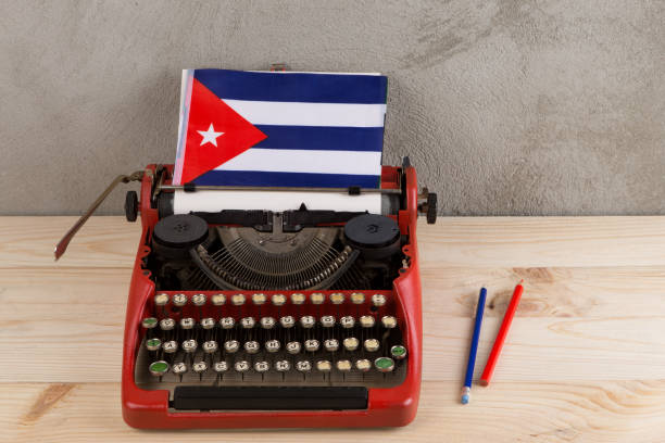 Political, news and education concept - red typewriter, flag of the Cuba, pencils on gray cement background stock photo