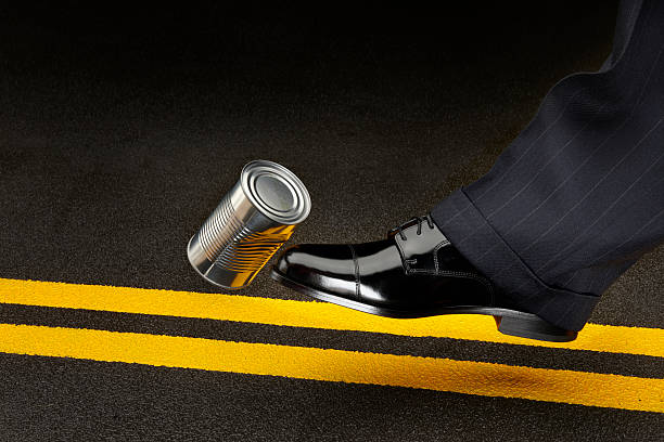 Politician kicking can down the road close up of politician's shoe kicking a dented shiny can down the road kicking stock pictures, royalty-free photos & images