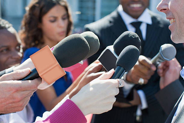 politician talking into reporters' microphones - journalist stockfoto's en -beelden
