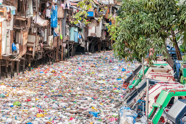 Polluted Urban River Shanties on stilts standing on garbage-filled river water pollution stock pictures, royalty-free photos & images