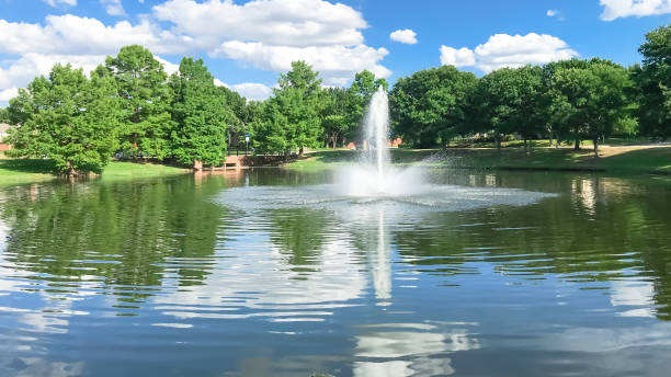 Pond with cloud reflection and water fountain in small American neighborhood stock photo