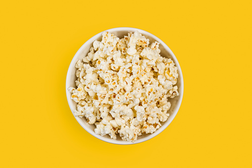 Popcorn in a white bowl on a yellow background
