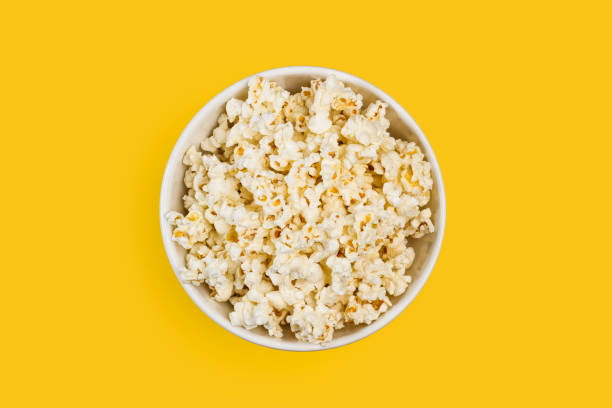 Popcorn in a white bowl Popcorn in a white bowl on a yellow background popcorn stock pictures, royalty-free photos & images