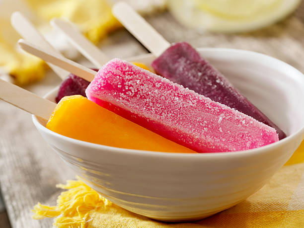 Popsicles "Cherry, Grape and Orange Popsicles at a Picnic with Lemonade in the Background- Photographed on Hasselblad H3D2-39mb Camera" flavored ice stock pictures, royalty-free photos & images