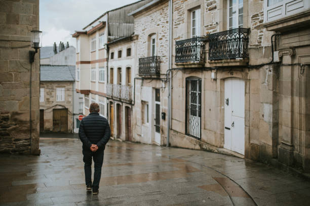 Popular street in Sarria village center, in a rainy day, with traditional buildings in both sides, and a man walking by the street. stock photo