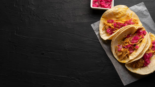 Pork meat tacos called cochinita pibil on a dark background. Mexican food stock photo