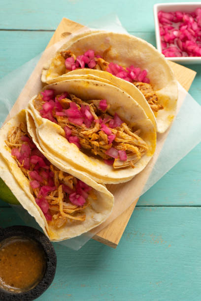 Pork meat tacos called cochinita pibil on a turquoise background. Mexican food stock photo