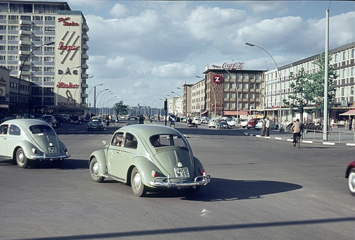 Lower Saxony, Germany, 1959. The Porschestrasse in Wolfsburg. Also: road traffic, buildings, passers-by and advertising signs.