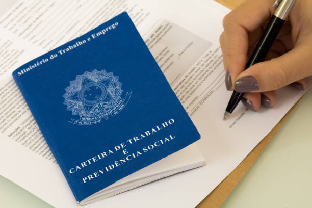 A portfolio of Brazilian workers (Translation "Work Permit, Ministry of Labor and Social Security Brazil CTPS"), female hand signing a work contract background. stock photo