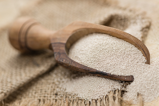 Heap of dried Yeast (detailed close-up shot) on wooden background