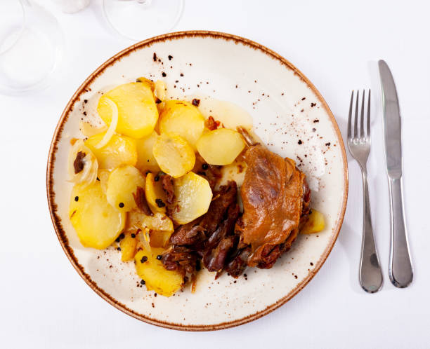 Portion of duck confit on table Just cooked portion of duck confit with fried poatoes served on table with serving pieces. duck meat photos stock pictures, royalty-free photos & images