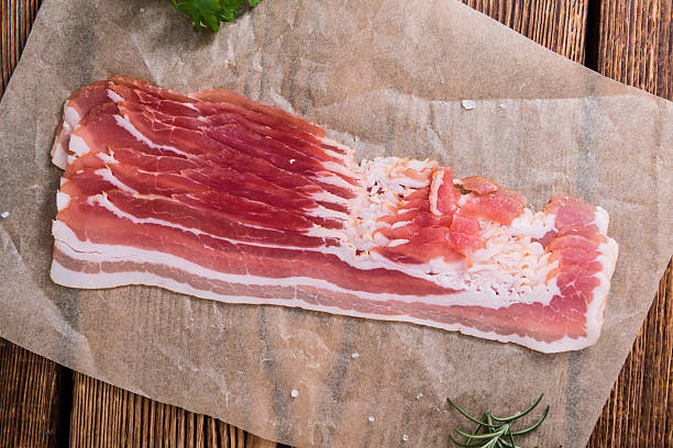 Portion of raw Bacon Portion of raw Bacon stripes on wooden background (selective focus) mottled stock pictures, royalty-free photos & images