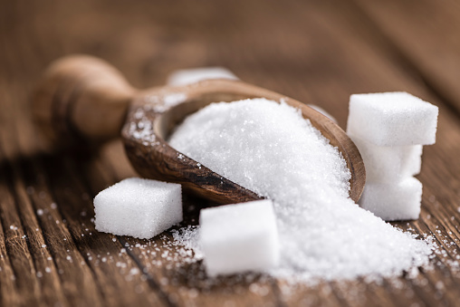 Portion of White Sugar (detailed close-up shot; selective focus) on wooden background