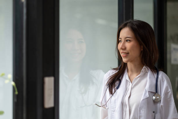 Portrait happy asian woman doctor looking outside in hospital stock photo