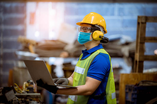 공장에서 오염과 바이러스를 보호하기 위해 안전 마스크를 착용하여 공장 스테이션에서 검사 및 생산 공정을 점검하고 있는 인물 노동자. - 직업 안전 보건 뉴스 사진 이미지